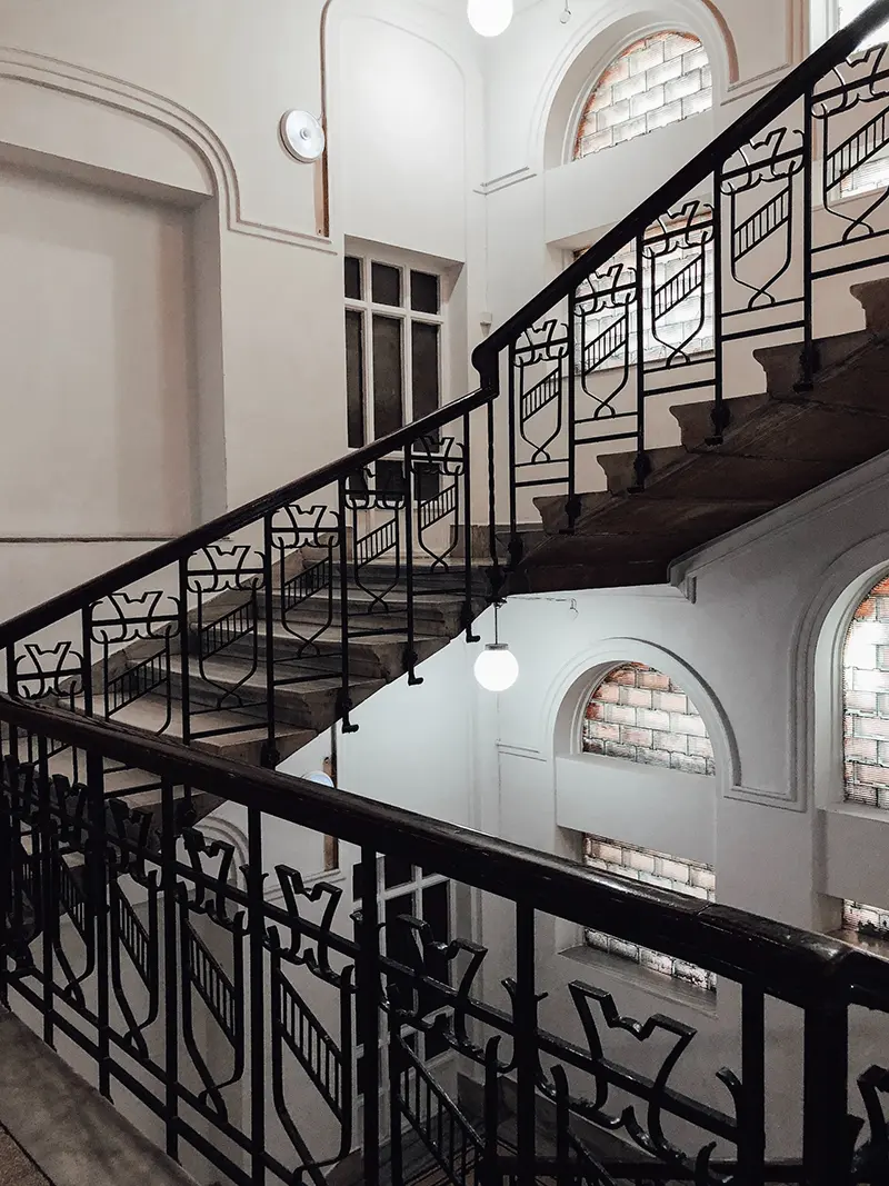 Escalera de hierro con barandilla decorativa en un edificio histórico, aportando elegancia y estilo arquitectónico.